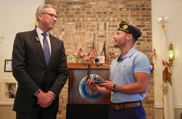 Treasurer Michael Frerichs, left, returns a Purple Heart belonging to WWII Army private Edward Gorski Jr. to his grandson, Shawn Gorski, at a ceremony at American Legion Post 75 in Geneva on June 12, 2025. (Stacey Wescott/Chicago Tribune)