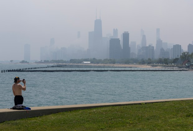 A man drinks from a bottle near Diversey Harbor on June 5, 2025, as the skyline is obscured by air pollution from Canadian wildfires. (Eileen T. Meslar/Chicago Tribune)