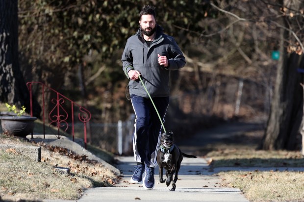 Kevin Conroy runs with his dog, Liam, in Chicago on March 12, 2025. Last autumn, they were attacked by a vicious dog, leaving Liam needing intensive veterinary care. (Terrence Antonio James/Chicago Tribune)