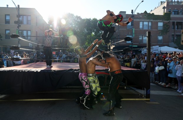 A wrestler named Lizard Man jumps onto three other wrestlers outside the ring during a Lucha Libre Mexican professional wrestling tag team event at the Lakeview Taco Fest on Sept. 7, 2024, in Chicago. (John J. Kim/Chicago Tribune)