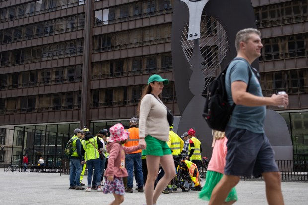 People walk past as volunteers prepare hours prior to the 'No Kings' protest in Daley Plaza on June 14, 2025. (Audrey Richardson/Chicago Tribune)