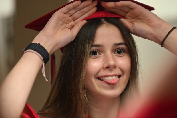 Having a fun moment while getting assistance from (unseen) Caroline Langanke of Lake Barrington to secure the mortarboard cap is Erin Salajean of Barrington before the Barrington High School graduation at Willow Creek Community Church in South Barrington on May 30, 2025. (Karie Angell Luc/Pioneer Press)