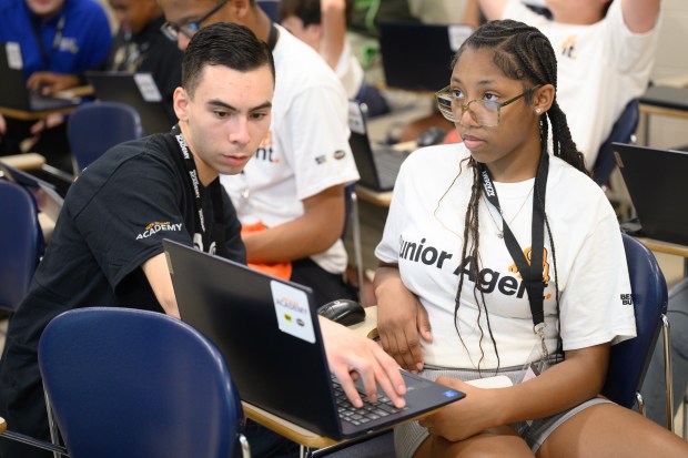 Best Buy sales associate Adrian Martinez, on left, helps student Aniyah Kelly create a 3D model of a table using CAD software during Indiana University Northwest's annual Kids College on Thursday, June 12, 2025. (Kyle Telechan/for the Post-Tribune)