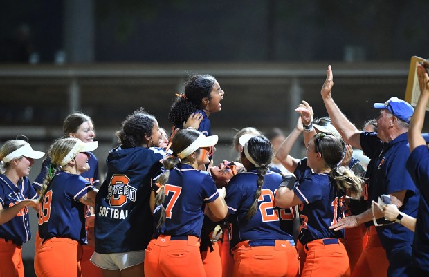 The Oswego softball team rallies around pitcher Jaelynn Anthony as catcher Kiyah Chavez (middle, in sunglasses) lifts her in the air after winning the Class 4A Benedictine Supersectional game against Marist on Monday, June 9, 2025 in Lisle.(Jon Cunningham for the Daily Southtown)