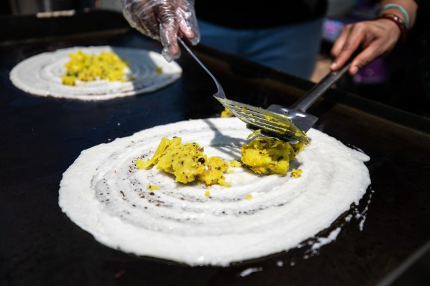 An employee at Hey Govindas Soulful Indian Cuisine makes dosas, a lentil and rice dish, at Vegandale in Grant Park on June 10, 2023. (Vincent D. Johnson/for the Chicago Tribune)