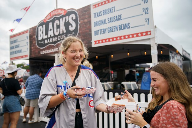 Morgan Schwerin, left, and Aerin Moberg eat Black's Barbecue while attending the final day of the Windy City Smokeout festival outside the United Center on Aug. 7, 2022, in Chicago. (Armando L. Sanchez/Chicago Tribune)