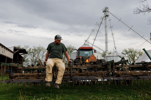 Hans Bishop removes debris from a soil finisher before planting uncoated corn seed on his farm, April 29, 2025, in Atlanta. (Armando L. Sanchez/Chicago Tribune)