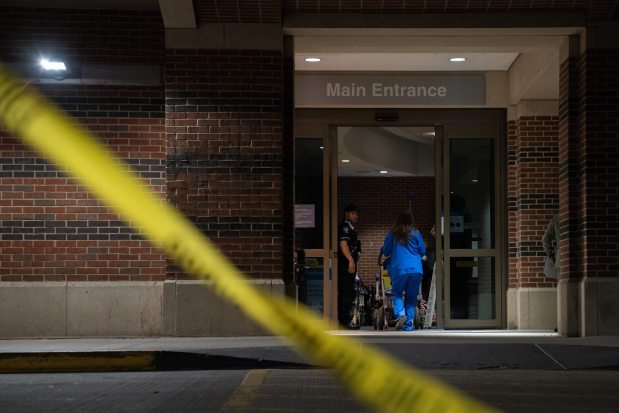 A police officer stands at the entrance of the Evanston Hospital emergency room as one person is removed from the building on June 6, 2025. One person was shot at the hospital Thursday night. The hospital was placed on lockdown following the shooting, only allowing employees to enter. (Audrey Richardson/Chicago Tribune)